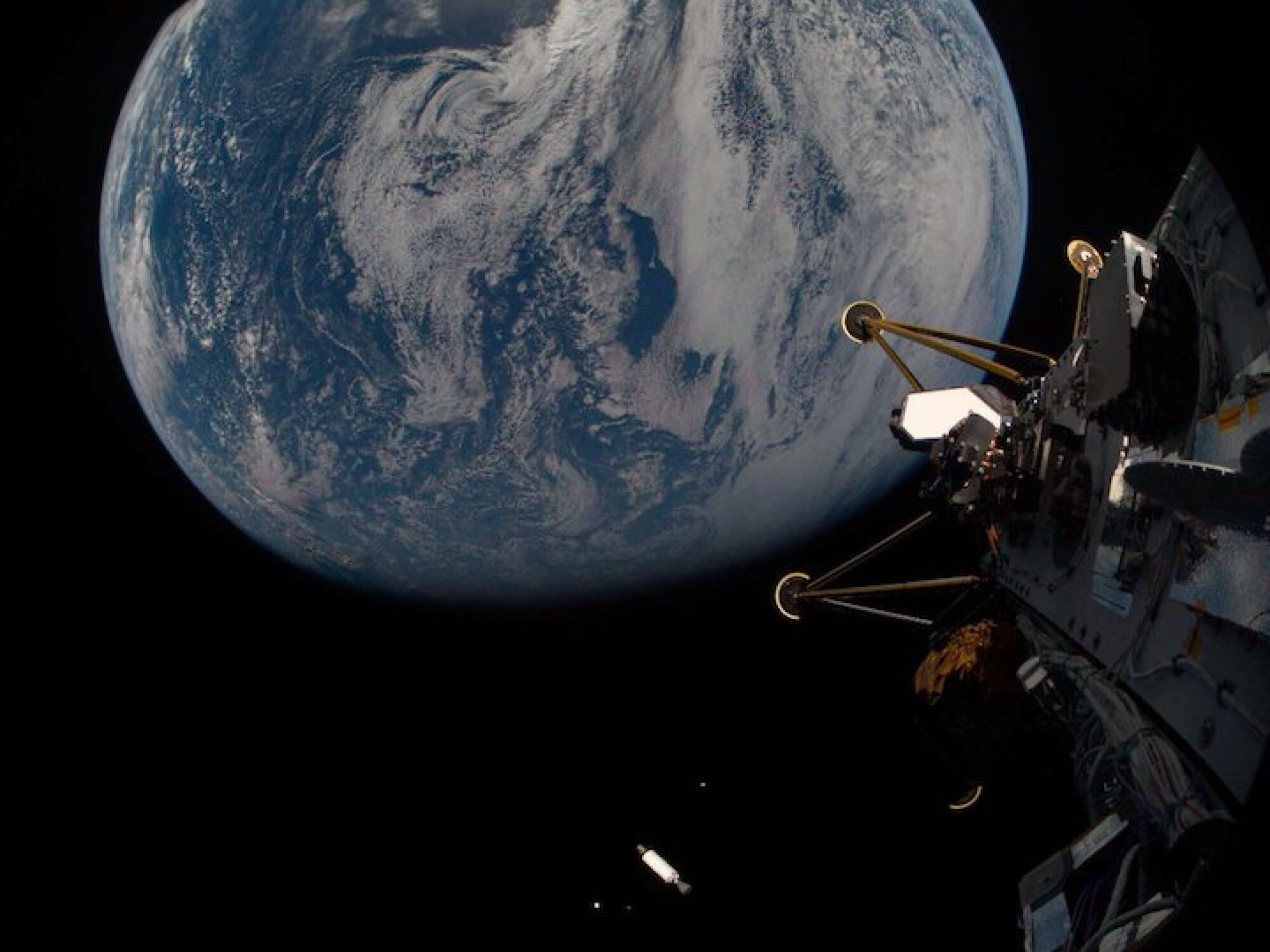 The legs of the Athena lander, a SpaceX rocket stage, and other payloads as viewed by the lander.