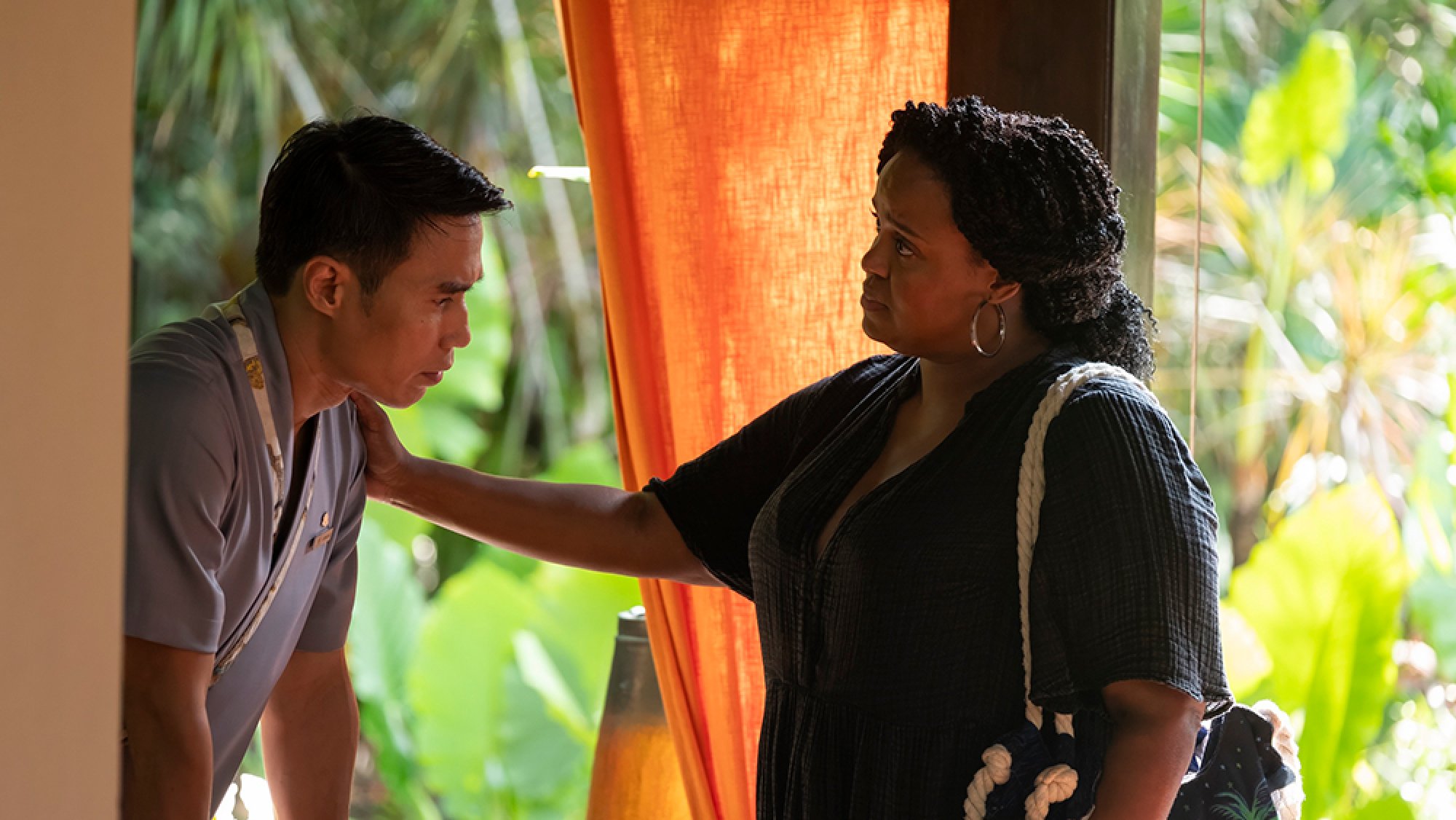 A woman stands next to a man with her hand on his shoulder.