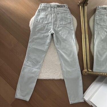Pair of jeans arraanged on rug in front of gold mirror