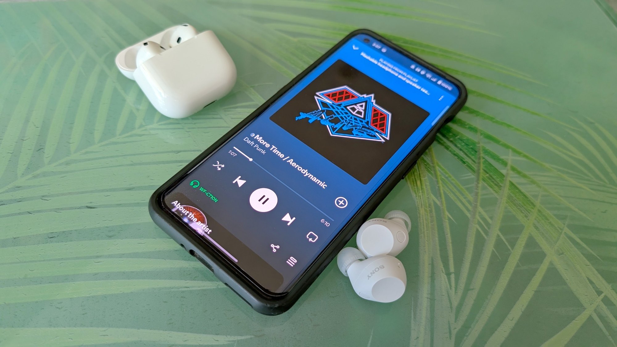 phone with Daft Punk song onscreen with sony earbuds and airpods near the phone