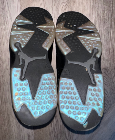 Bottoms of a pair of iridescent blue Air Jordan sneakers on hardwood floor